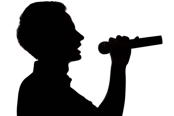 Silueta de un joven talentoso cantando en un micrófono
 - Foto, imagen