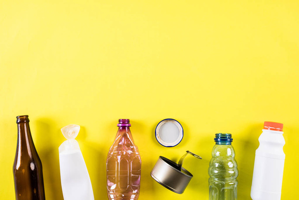 Bovenaanzicht van verschillende vuilnis materialen voor recycling op gele achtergrond. Recycling, milieu en eco concept - Foto, afbeelding