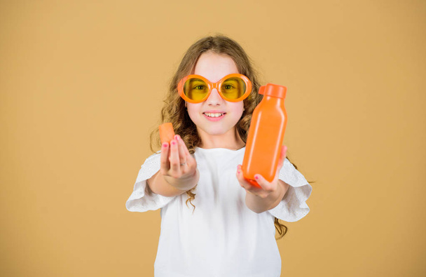 Vitamin nutrition. Fashion kid sunglasses drink refreshing vitamin juice. Health care. Summer vitamin diet. Happy childhood. Natural vitamin source. Girl eat carrot vegetable and drink carrot juice - Fotó, kép