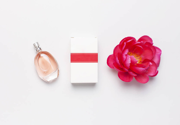 淡い灰色の背景上のビューフラットレイコピースペース上の香水瓶とピンクの花のピオ。香水、化粧品、女性アクセサリー、フレグランスコレクション。デリケートピンクの香水ボトル - 写真・画像