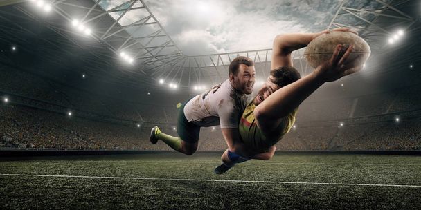zwei männliche Rugbyspieler kämpfen im Flug um den Ball im professionellen Rugbystadion - Foto, Bild