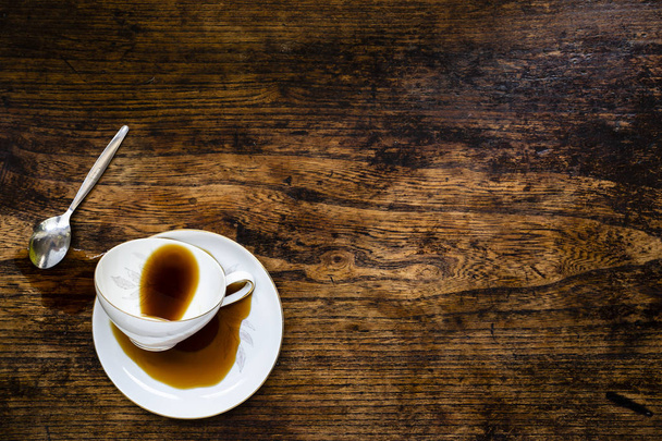 Kiömlött kávé mellett a szüreti csésze sötét woorden asztalra - Fotó, kép