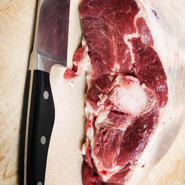 Lamb raw on a wooden board with a knife - Φωτογραφία, εικόνα