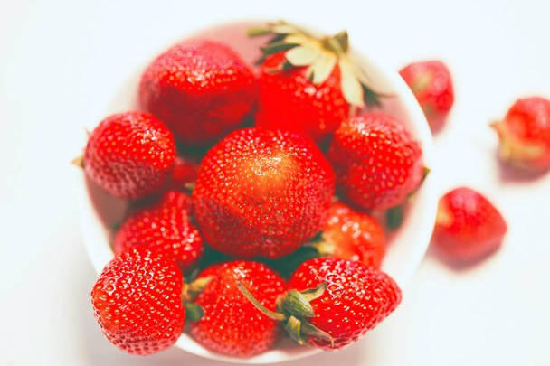 Cuenco blanco con fresas rojas frescas sobre un fondo blanco clo
 - Foto, imagen