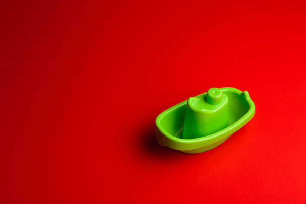 little green plastic toy ship on the red background with copy space. - Fotografie, Obrázek