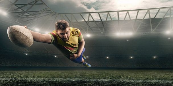 Грязный регбист ловит мяч в полете на профессиональном регбийном стадионе
 - Фото, изображение