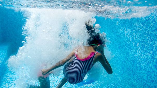 Víz alatti kép két tizenéves lány jumping és búvárkodás uszodában a tornateremben - Fotó, kép