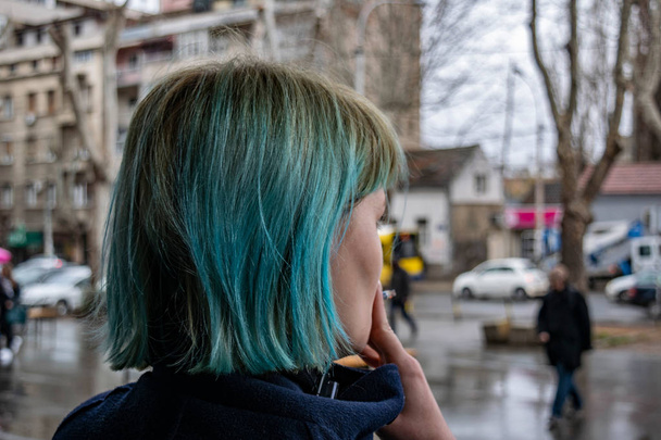 Ένα κορίτσι με μπλε μαλλιά καπνίζει ένα πούρο - Φωτογραφία, εικόνα