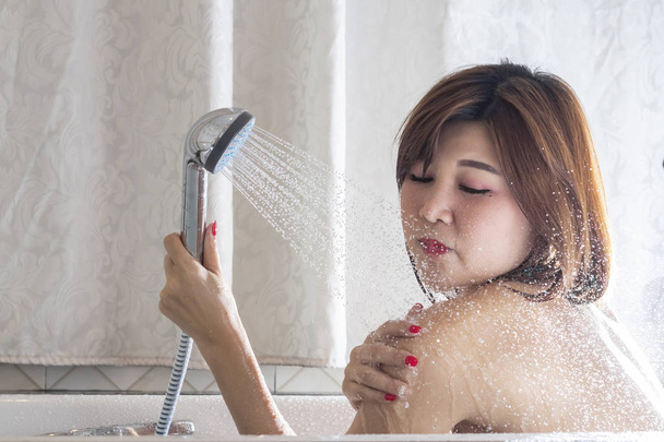 Ázsiai nő vesz zuhany az ő fürdőszoba - Fotó, kép