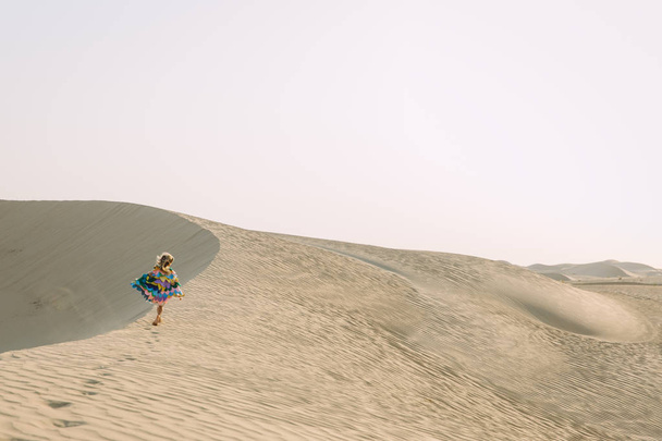 Kleines Mädchen mit bunten Flügeln läuft in der Wüste  - Foto, Bild