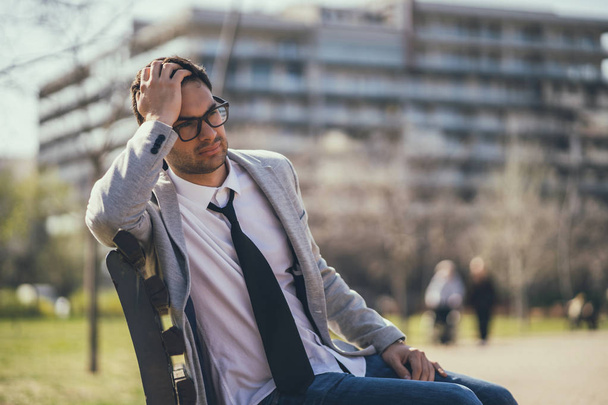 Young businessman is very tired. He is relaxing in park.  - 写真・画像