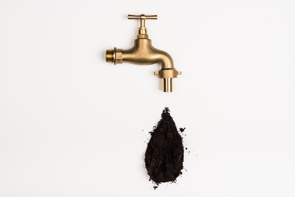 top view of faucet and black soil on white - Fotó, kép