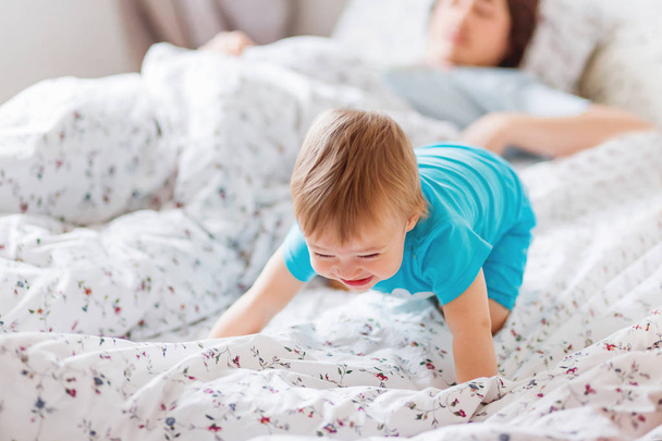 Man with baby in bed. Cute cozy home background. Morning bedtime. Smiling father with laughing son. Kid in blue clothes. - Foto, Imagen