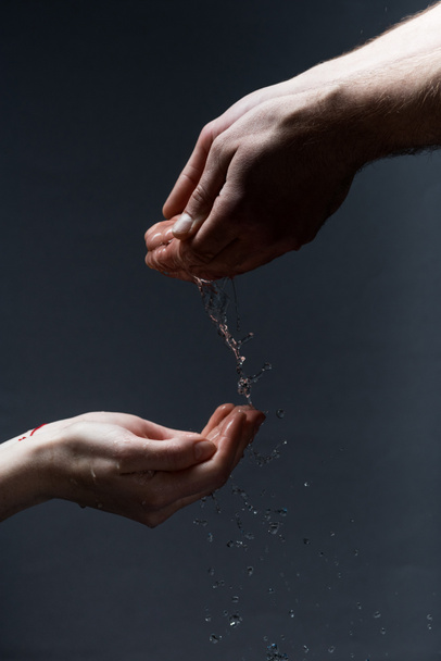 cropped view of man and woman with water drops on dark - Fotografie, Obrázek