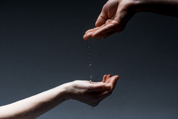 cropped view of man and woman with water drops on dark - Foto, Imagem