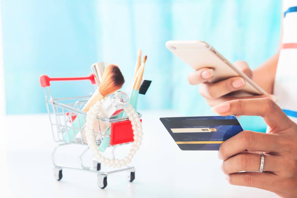 Женщина с помощью смартфона и кредитных карт покупки предметов красоты. Интернет-магазины, электронная оплата
 - Фото, изображение