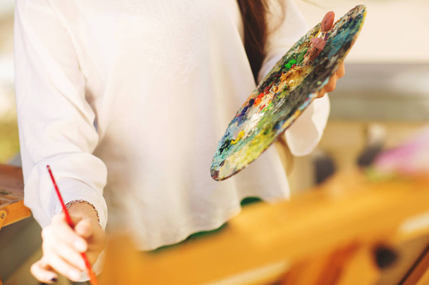 Молодая брюнетка-художница держит в руках кисть и палитру. Закрывай. Концепция искусства
 - Фото, изображение