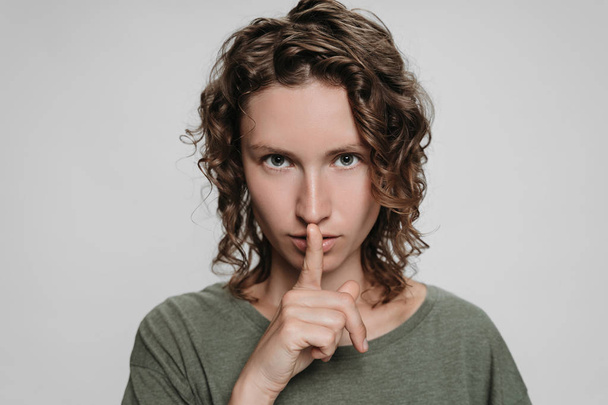 Curly caucasian young woman looks serious, holding finger at her - Photo, Image
