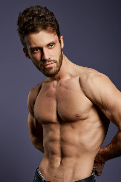 shirtless strong well-built guy standing in the studio with black wall - Foto, immagini