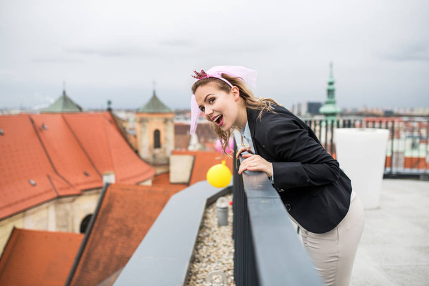 A woman with princess headband on party outdoors on roof terrace in city. - Fotó, kép