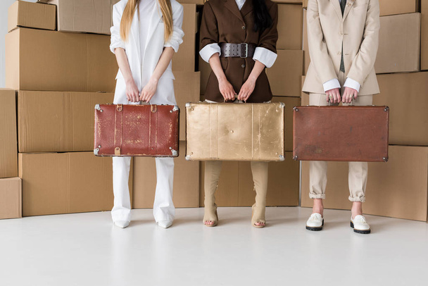 vista recortada de las niñas de pie con maletas cerca de cajas en blanco
  - Foto, Imagen