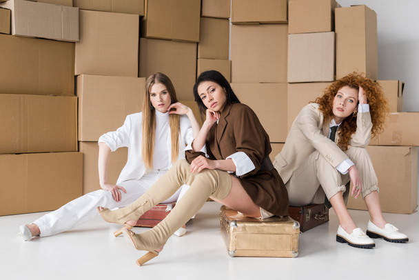 african american girl sitting on luggage near women and boxes on white  - Foto, Imagen