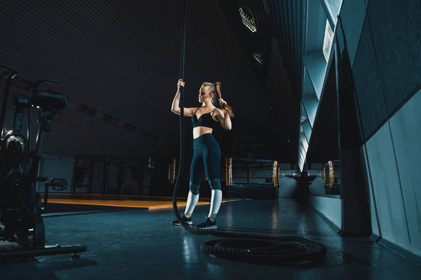 Full length wide angle shot of a woman performing rope climbs at - Photo, Image