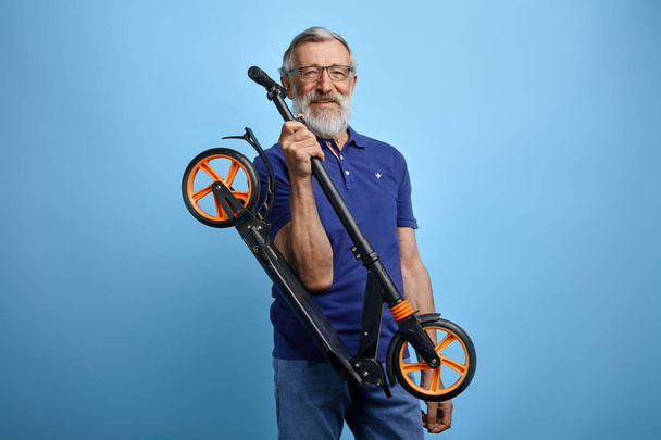 şık rahat giysiler içinde aktif yakışıklı yaşlı adam scooter binmek için gidiyor. - Fotoğraf, Görsel