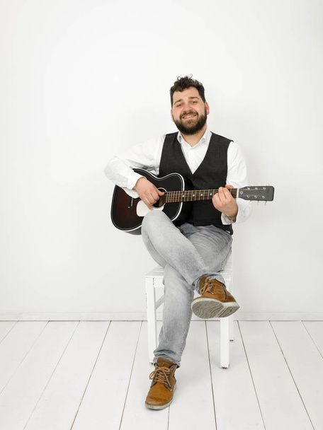 man with black hair and beard playing acoustic guitar on white background - Fotó, kép