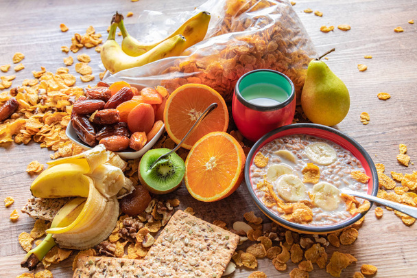 Ontbijt geserveerd met melk, jus d'orange, kiwi, ontbijtgranen en banaan. Evenwichtige voeding. - Foto, afbeelding