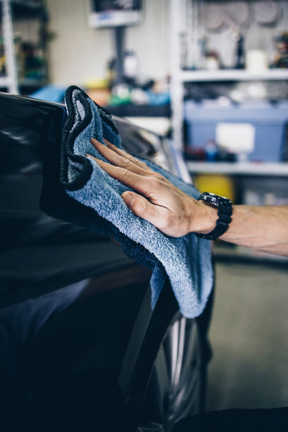 A man cleaning car with microfiber cloth, car detailing (or valeting) concept. Selective focus. - 写真・画像