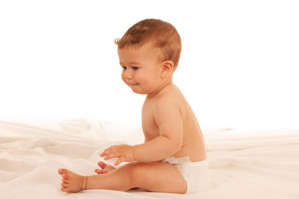 Hapy baby boy in playing on bed isolated over white  - Φωτογραφία, εικόνα