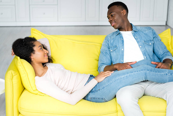 african american woman lying on couch and looking at boyfriend - Fotó, kép