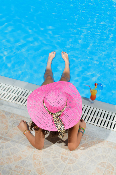 Woman sitting on the ledge of the pool. - Zdjęcie, obraz