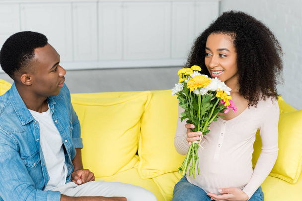 pregnant african american holding flowers in hand, and looking at boyfriend - Foto, Imagen