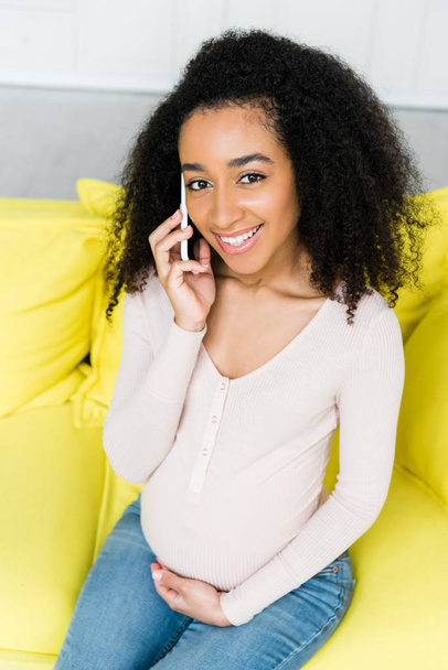magas látószögű nézet a boldog és terhes afro-amerikai nő beszél smartphone - Fotó, kép