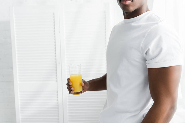 cropped view of african american man holding glass of juice in hand - Photo, image