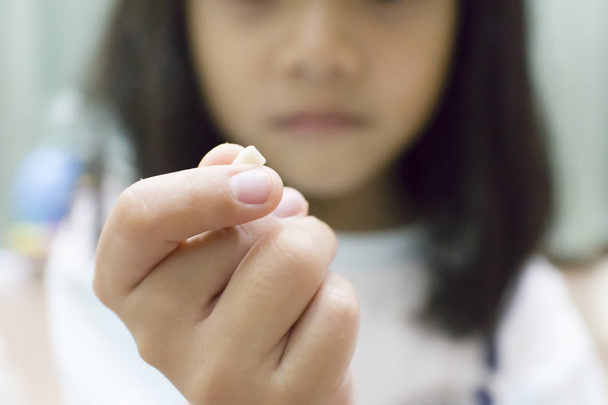 little girl holds her first falling milk teeth - Photo, Image