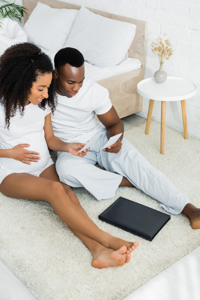 high angle view of pregnant african american woman looking at picture with boyfriend - Photo, Image
