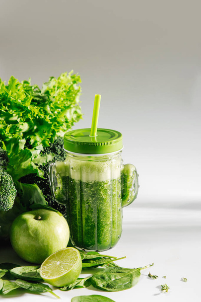Green smoothie in cute glass jar shape of cactus with spinach and green fruits and vegetables on white table. Vegetarian food. Detox and diet concept.  - Fotó, kép