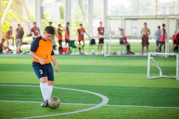 アジアの少年サッカー選手スピードは、アーティフでゴールにボールを撃つために実行します - 写真・画像
