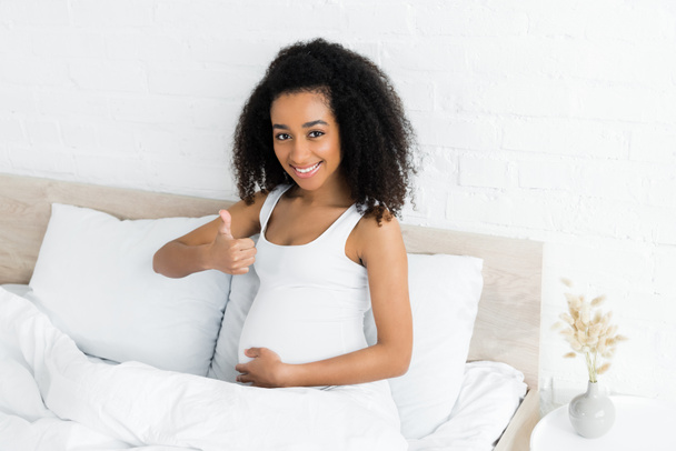 щаслива і вагітна афроамериканка показує великий палець вгору
 - Фото, зображення