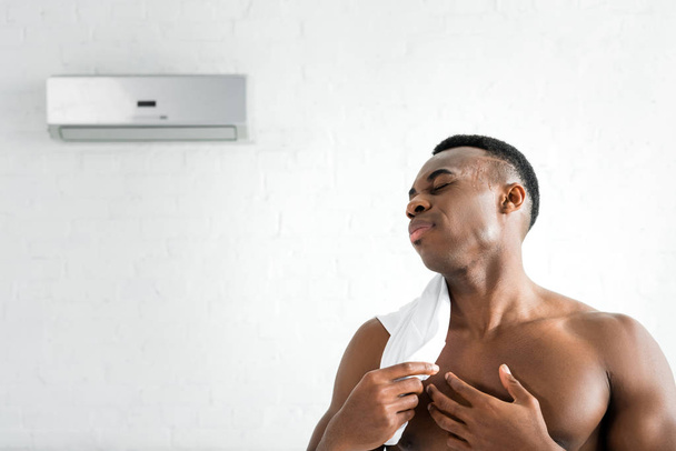 hombre afroamericano de pie en la habitación con aire acondicionado
 - Foto, Imagen