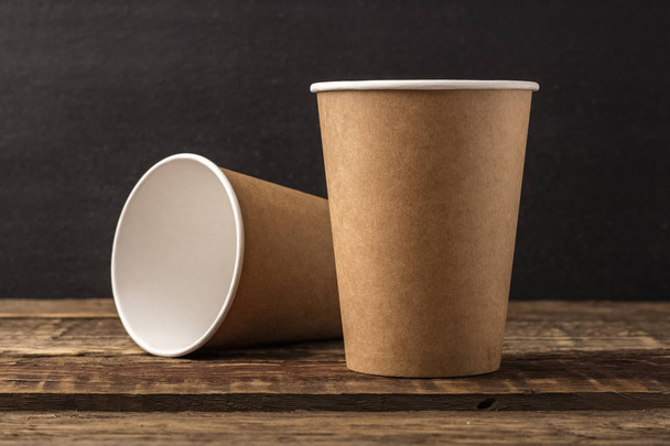 Disposable cup from craft on a wooden table with copy space. dark Background, mockup - Fotó, kép