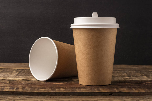 Disposable cup from Kraft on a wooden table with copy space. Black Background, mockup - Valokuva, kuva