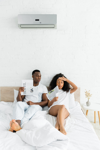 pareja afroamericana sentada en la cama en la habitación con temperatura de calor y aire acondicionado
 - Foto, Imagen