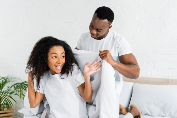 african american man covering girlfriend with white blanket - Фото, зображення