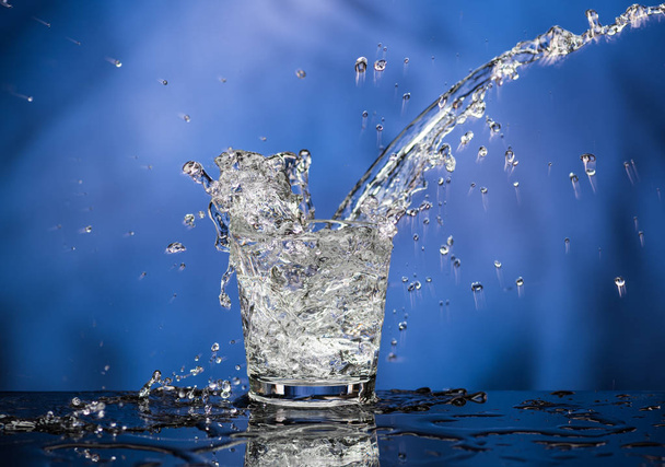 Glass with vodka and a big splash on a colored background - Foto, imagen
