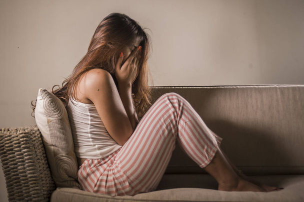 young sad and depressed woman in pajamas at at home couch crying desperate feeling frustrated and upset suffering stress and depression after breakup - Fotografie, Obrázek