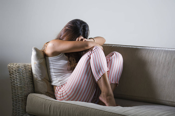 young sad and depressed woman in pajamas at at home couch crying desperate feeling frustrated and upset suffering stress and depression after breakup - Fotografie, Obrázek